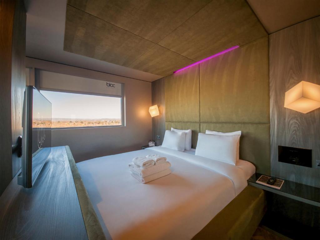 Compact Bloc hotel room with an olive headboard and pink lighting