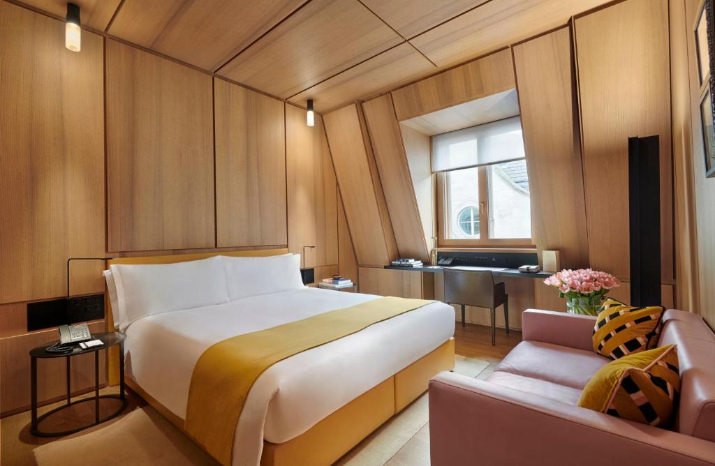 Hotel room with wood-panelled walls, a yellow bed runner and a pink sofa