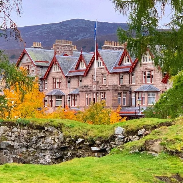 Stone highland hotel with autumn trees and a mountain behind