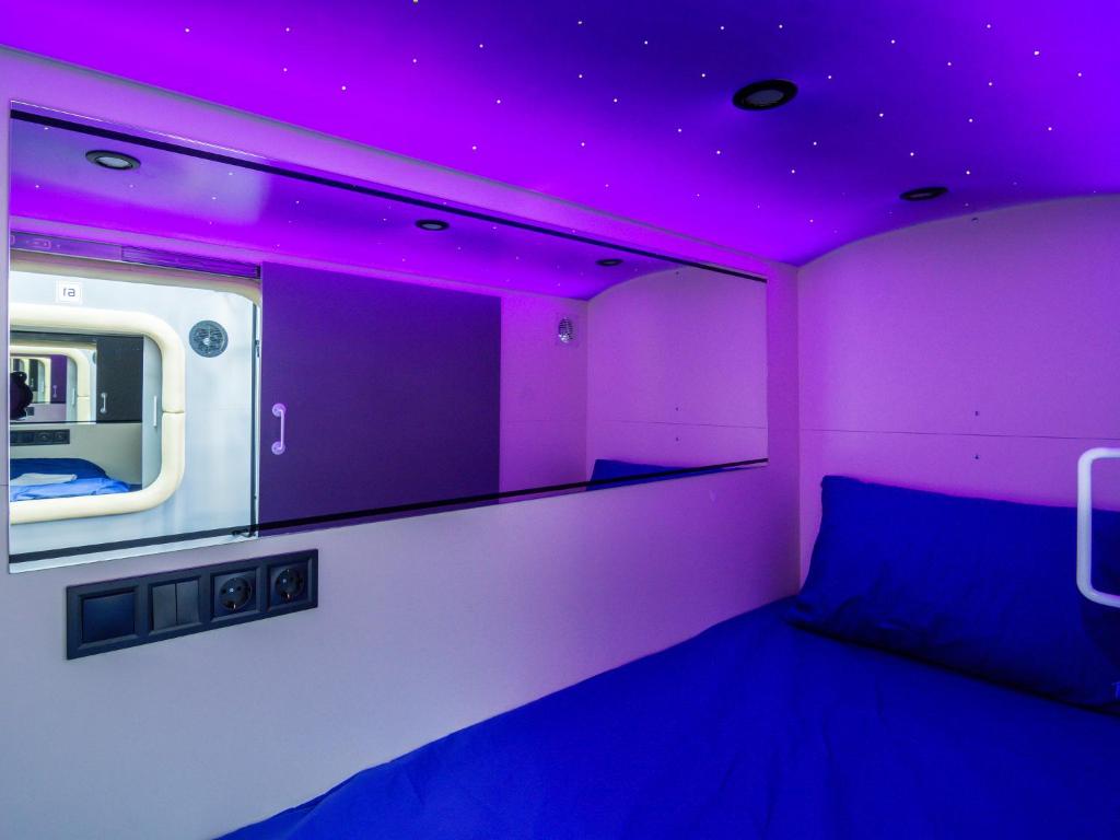 Sleeping capsule with a purple starlit ceiling and blue bedding