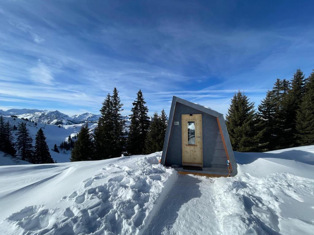 Modern cabin in deep snow with alpine peaks behind