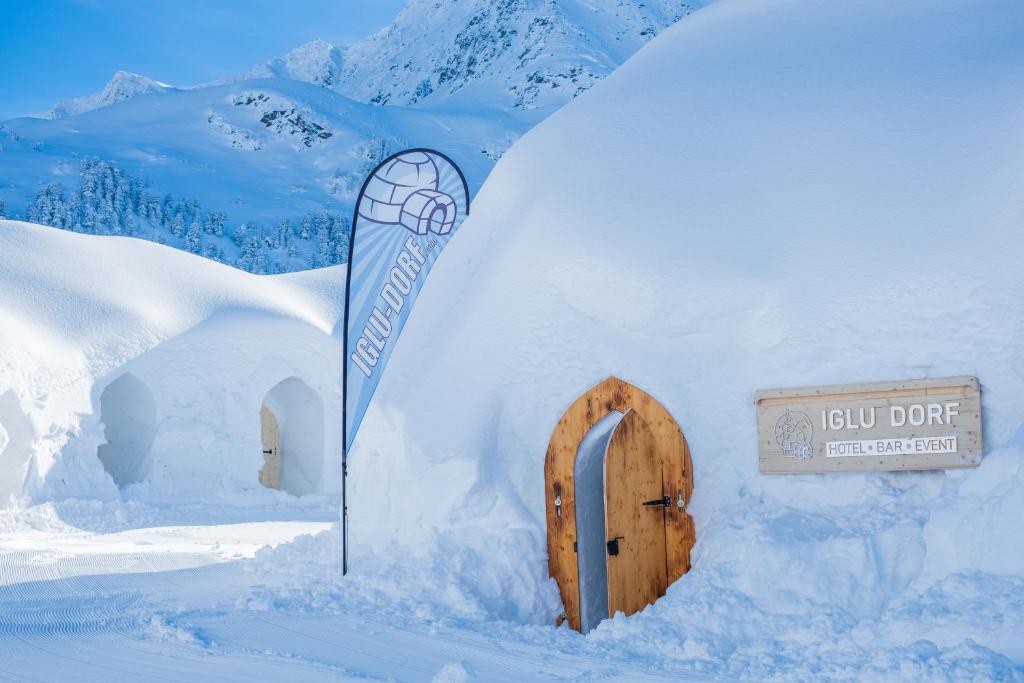 Igloo village in snow with wooden doors and mountain peaks