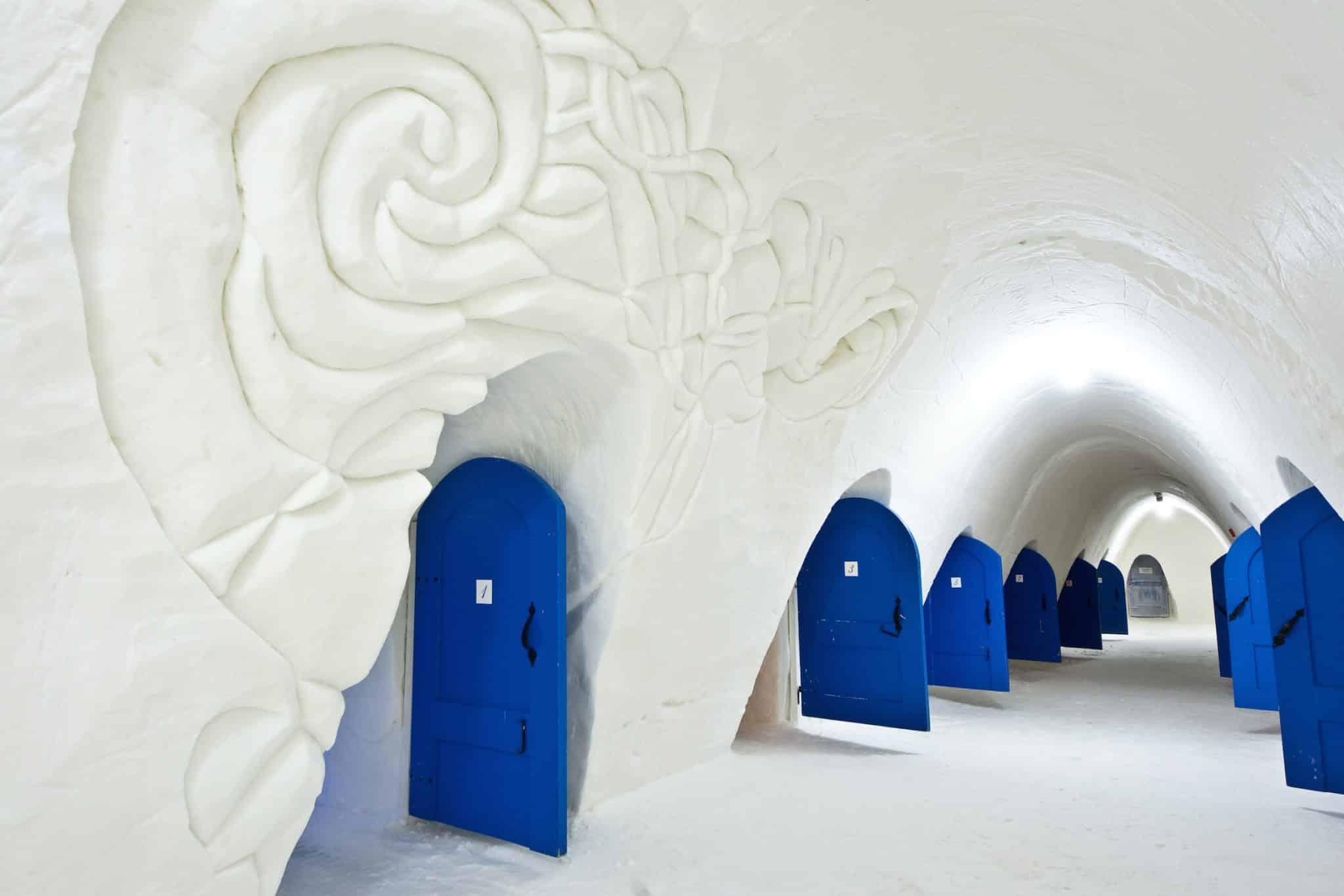 Ice hotel corridor with carved snow walls and blue doors