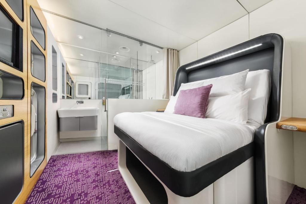 Modern cabin room with white bedding, a purple carpet and a glass shower